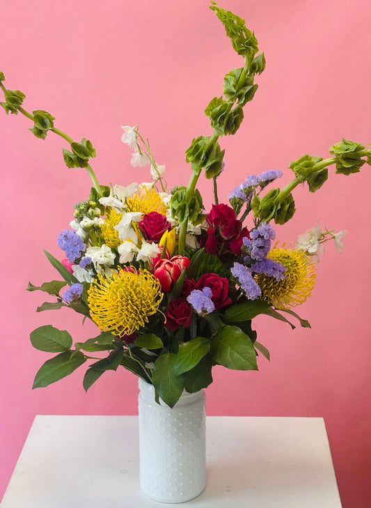 white vase, bells of ireland, tulips, tropicals