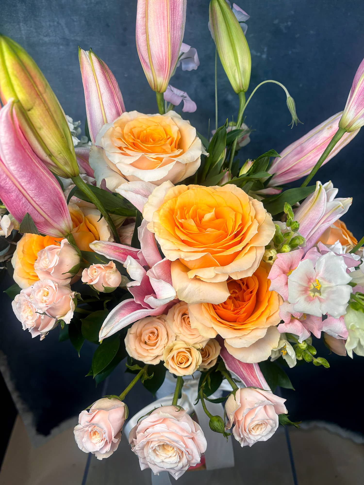 Bouquet of flowers including roses and lilies with a dark background
